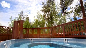 A hot tub with a wooden deck and a fence, surrounded by trees. - Dog friendly, hot tub, free shuttle (Keystone)