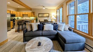 A modern living room with a sectional sofa, a marble coffee table, and a kitchen in the background. - Dog friendly, hot tub, free shuttle (Keystone)