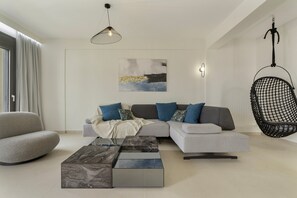 Een moderne woonkamer met een hoekbank, een hangstoel en een marmeren salontafel.
