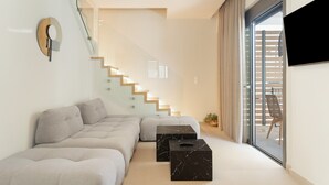 A modern living room with a sectional sofa, a glass staircase, and a sliding glass door leading to an outdoor area. - Villa 'Mella Roa -  Onyx' with Sea View, Wi-Fi and Air Conditioning (?e???????)