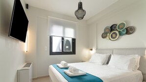 A hotel room with a bed, a flat-screen TV, a heater, and a wall-mounted light fixture. - Villa 'Mella Roa -  Onyx' with Sea View, Wi-Fi and Air Conditioning (?e???????)