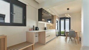 A modern kitchen with a built-in oven, a dining area with a table and chairs, and a bench. - Villa 'Mella Roa -  Onyx' with Sea View, Wi-Fi and Air Conditioning (?e???????)