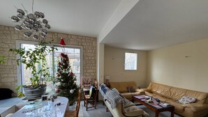 Una sala de estar con pared de piedra, un árbol de Navidad, una mesa de comedor y un sofá de cuero.