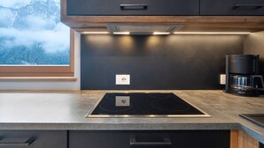 A modern kitchen with a built-in stove, a coffee maker, and a window with a mountain view. - Apartment 'Schmetterling' with Mountain View, Shared Terrace and Wi-Fi (Seis)