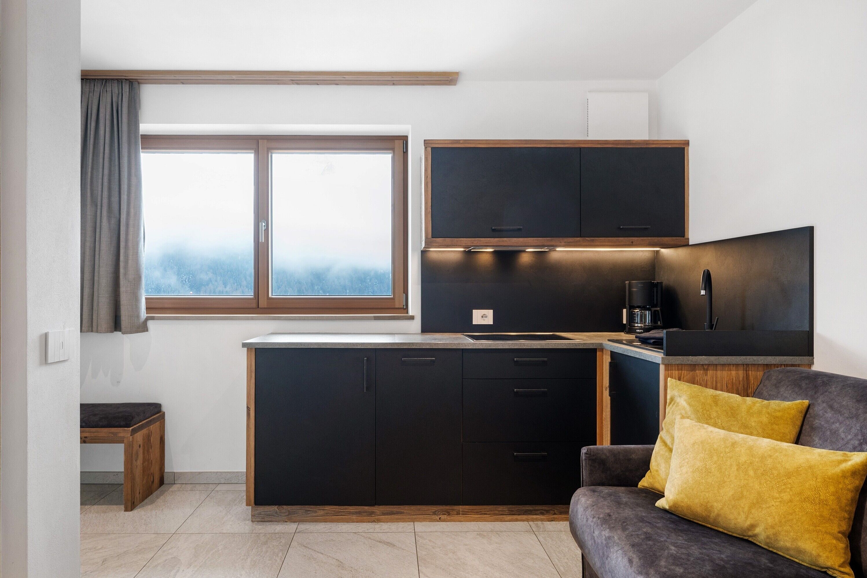 A modern kitchen with dark cabinetry, a built-in oven, and a coffee maker.