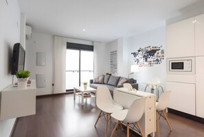 Un salon moderne comprenant un canapé, une table à manger avec des chaises, un téléviseur et un mur orné d’une carte du monde.