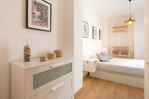 Un dormitorio moderno con cama, mesita de noche, lámpara y una obra de arte en la pared.