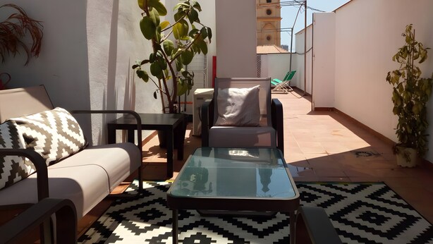 A rooftop terrace with a sofa, a table, and potted plants. - Apartment 'Quiet, Bright and Central' with Shared Terrace, Wi-Fi and Air Conditioning (Málaga)