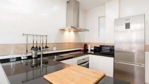 A modern kitchen with stainless steel appliances, a wooden cutting board, and a sleek black countertop. - Apartment 'Quiet, Bright and Central' with Shared Terrace, Wi-Fi and Air Conditioning (Málaga)