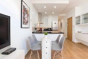 Una cocina moderna con comedor, televisor de pantalla plana y una obra de arte enmarcada en la pared.