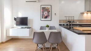 A modern kitchen with a dining area, a flat-screen TV, and a framed artwork on the wall. - Apartment 'Quiet, Bright and Central' with Shared Terrace, Wi-Fi and Air Conditioning (Málaga)