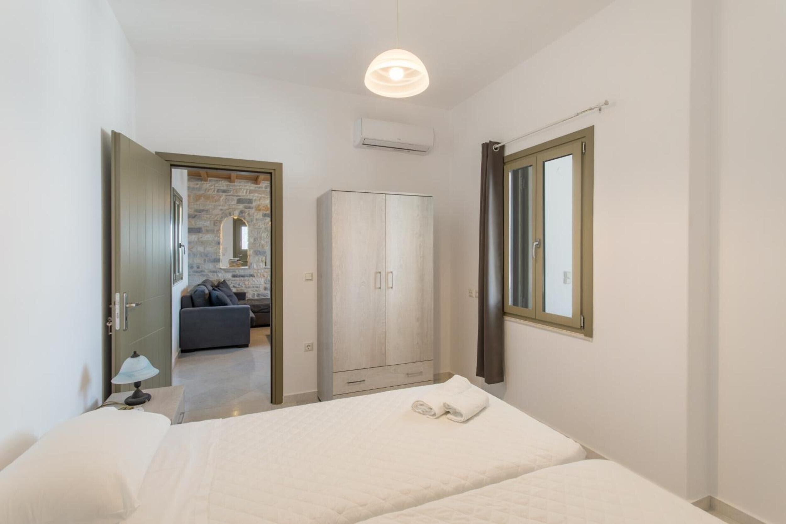 A bedroom with a bed, a wardrobe, a mirror, and a window.