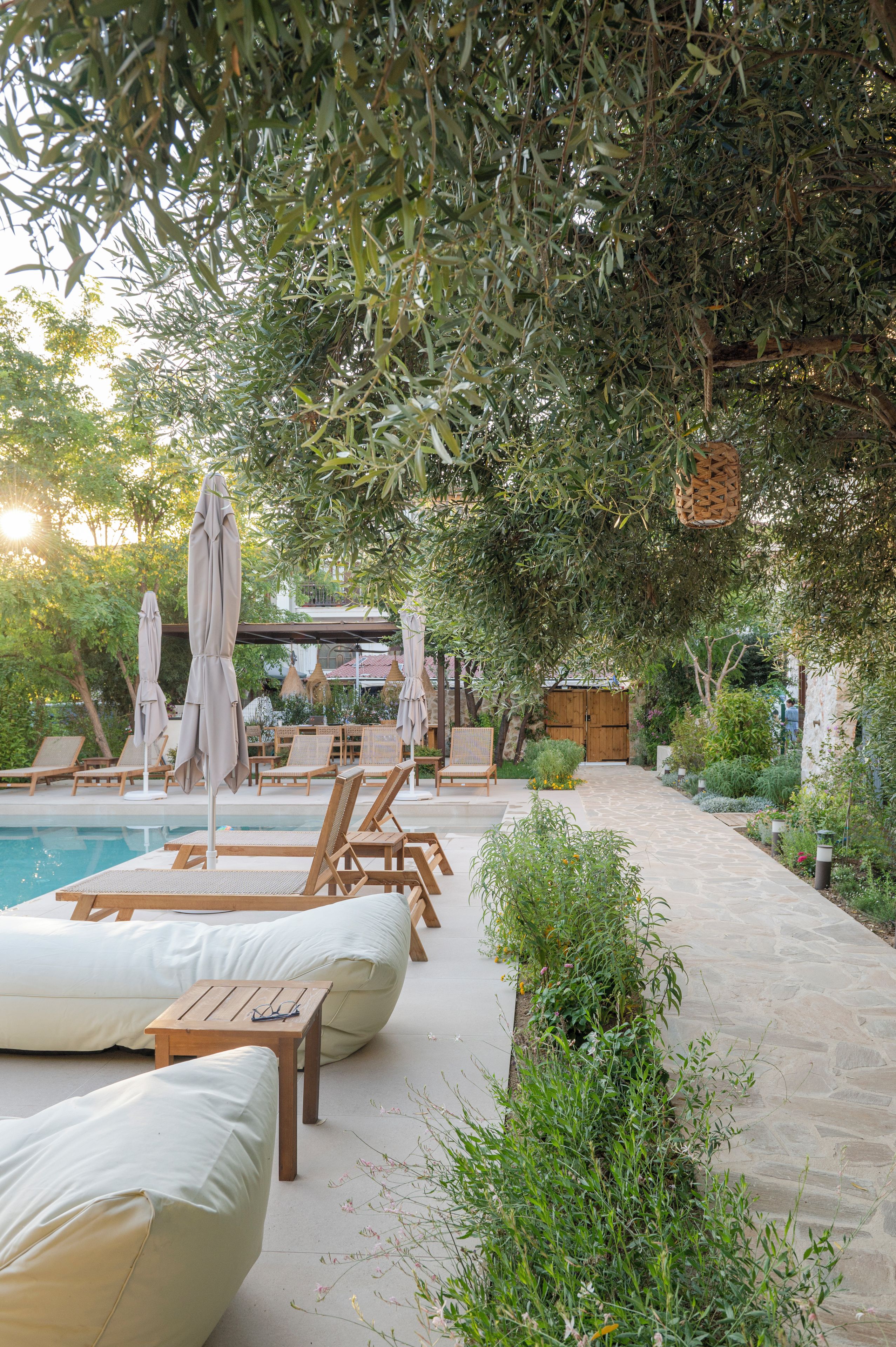 A poolside area with lounge chairs, umbrellas, and a stone pathway.