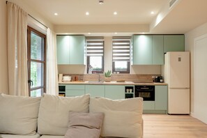 A modern kitchen with light green cabinets, a white refrigerator, and a wooden countertop. - Elea 1 - Modern, comfortable furnishings, close to the beach (Ierissos)
