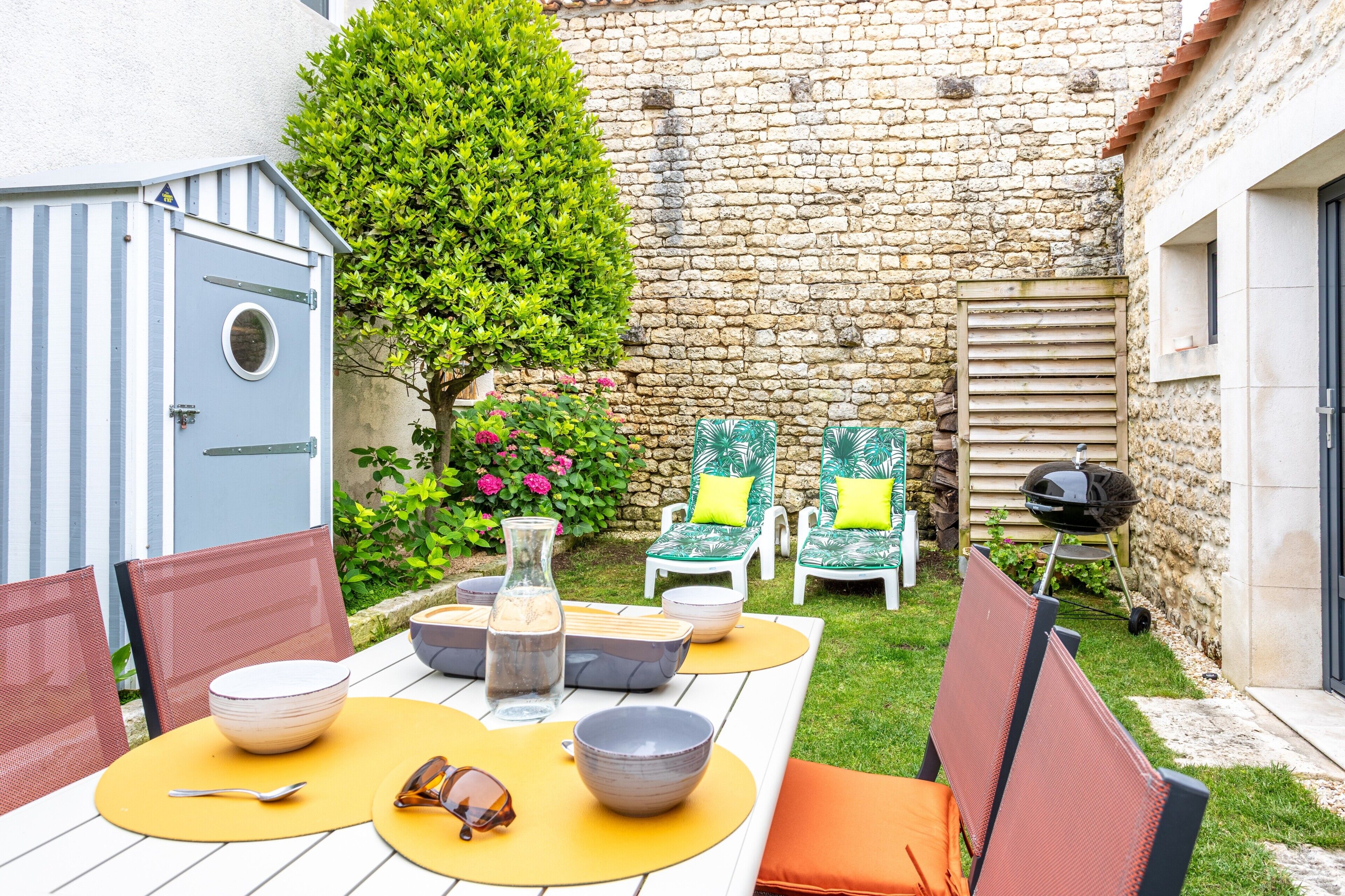 A patio with a table, chairs, and a barbecue grill.