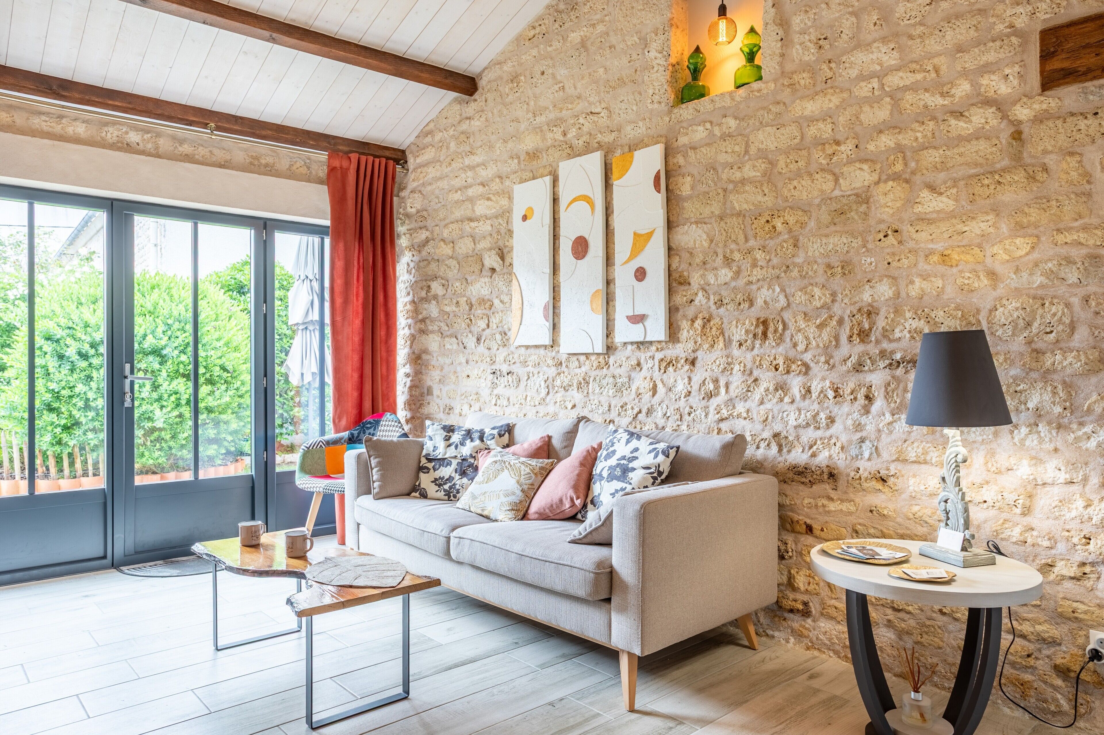 A cozy living room with a stone wall, a sofa, a coffee table, and a lamp.