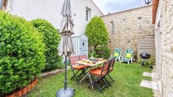 Een terras met een tafel, stoelen, een barbecue en een stenen muur.