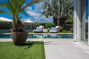 Relax by the pool surrounded by lush greenery and comfortable lounge chairs.