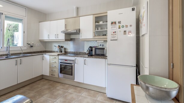 Una cocina moderna con armarios blancos, horno de acero inoxidable, microondas y refrigerador.
