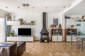 Un salon moderne avec une cheminée, un téléviseur et un coin repas.