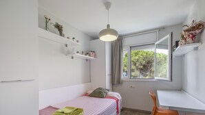 Un dormitorio con una cama individual, un escritorio y una ventana con vista a árboles.
