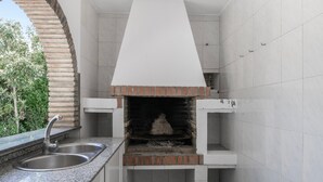 A kitchen with a built-in brick oven, a sink, and a window overlooking greenery. - Holiday Home 'Manuel' with Shared Pool, Wi-Fi and Air Conditioning (Conil)