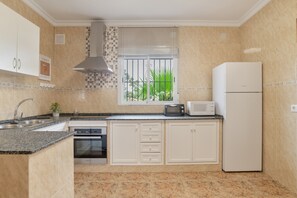 A kitchen with a microwave, toaster, sink, oven, and a refrigerator.
