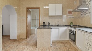 A modern kitchen with a central island, built-in oven, and white cabinetry. - Holiday Home 'Manuel' with Shared Pool, Wi-Fi and Air Conditioning (Conil)