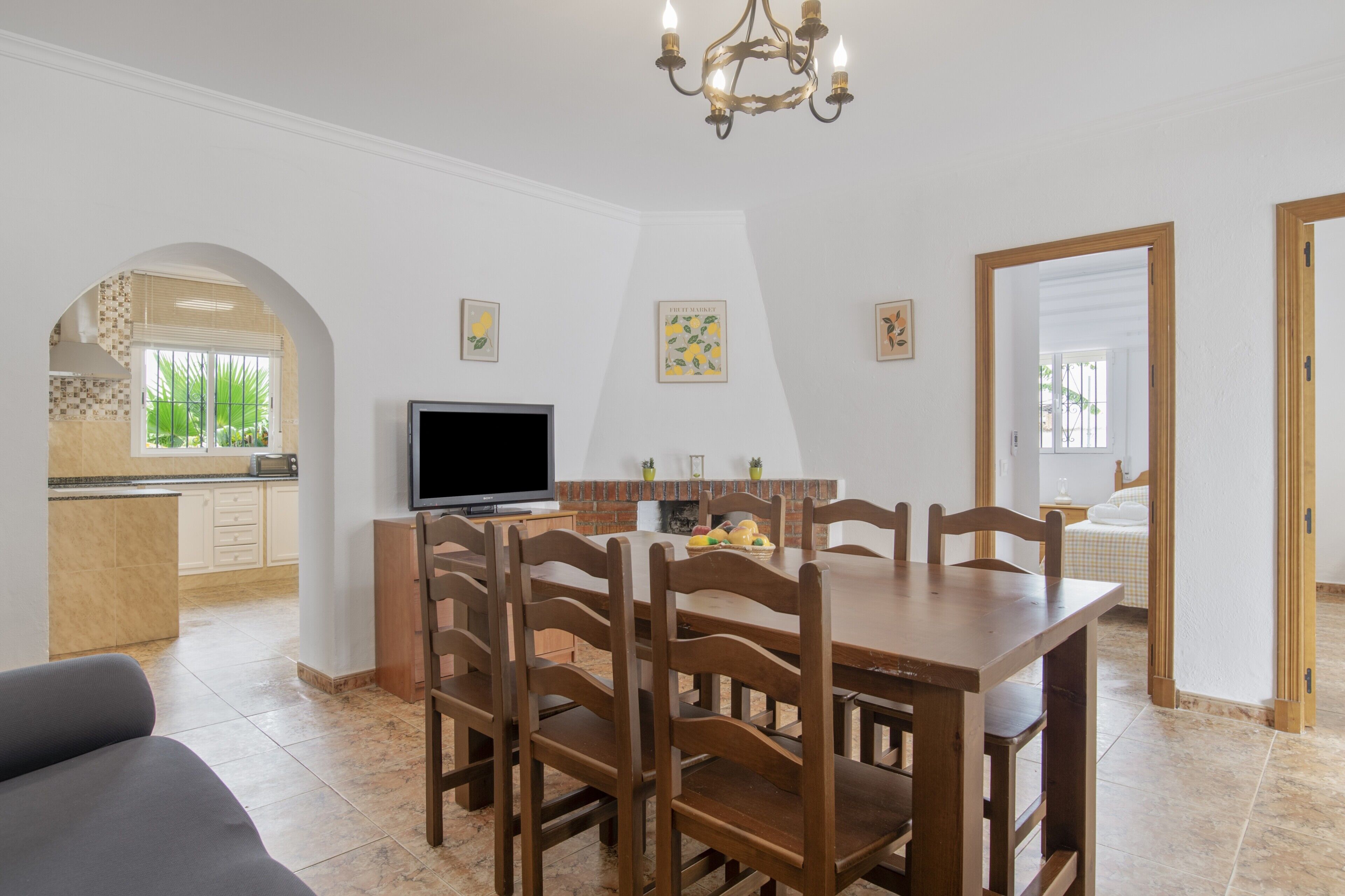 A dining area with a wooden table and chairs, a television, and artwork on the walls.