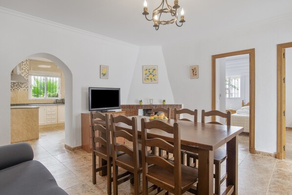 A dining area with a wooden table and chairs, a television, and artwork on the walls.