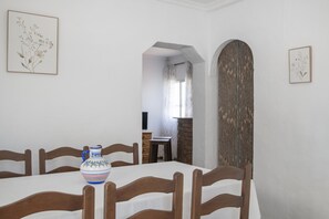 A dining area with a table, chairs, a vase, and framed artwork on the walls.