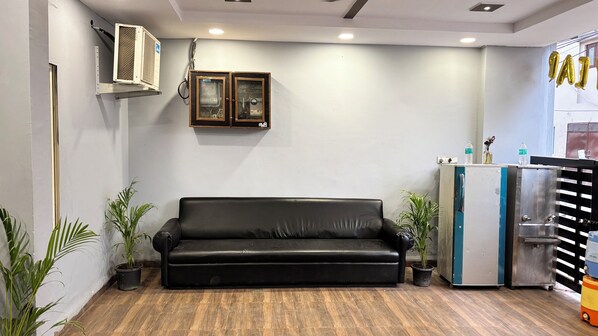 A room with a black leather sofa, a small cabinet, and a water dispenser. - Wishotel Premier Grand Ambrosia (Indore)