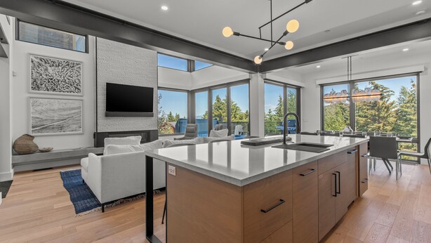A modern kitchen with a large island, built-in appliances, and large windows offering views of the outdoors. - Modern Home in Canyons Village by InvitedHome | Hot Tub, Game Room, Hike, Bike (Park City)