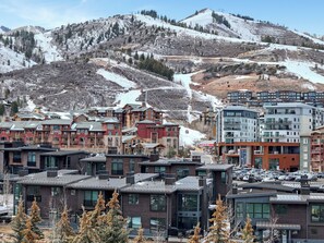 A mountain town with modern buildings, a ski lift, and snow-covered slopes.