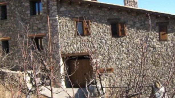 A stone building with multiple windows and a door, surrounded by bare trees.