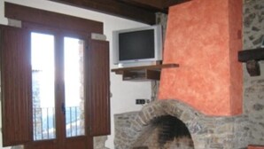 A stone fireplace with a television above it, a wooden door, and a balcony.