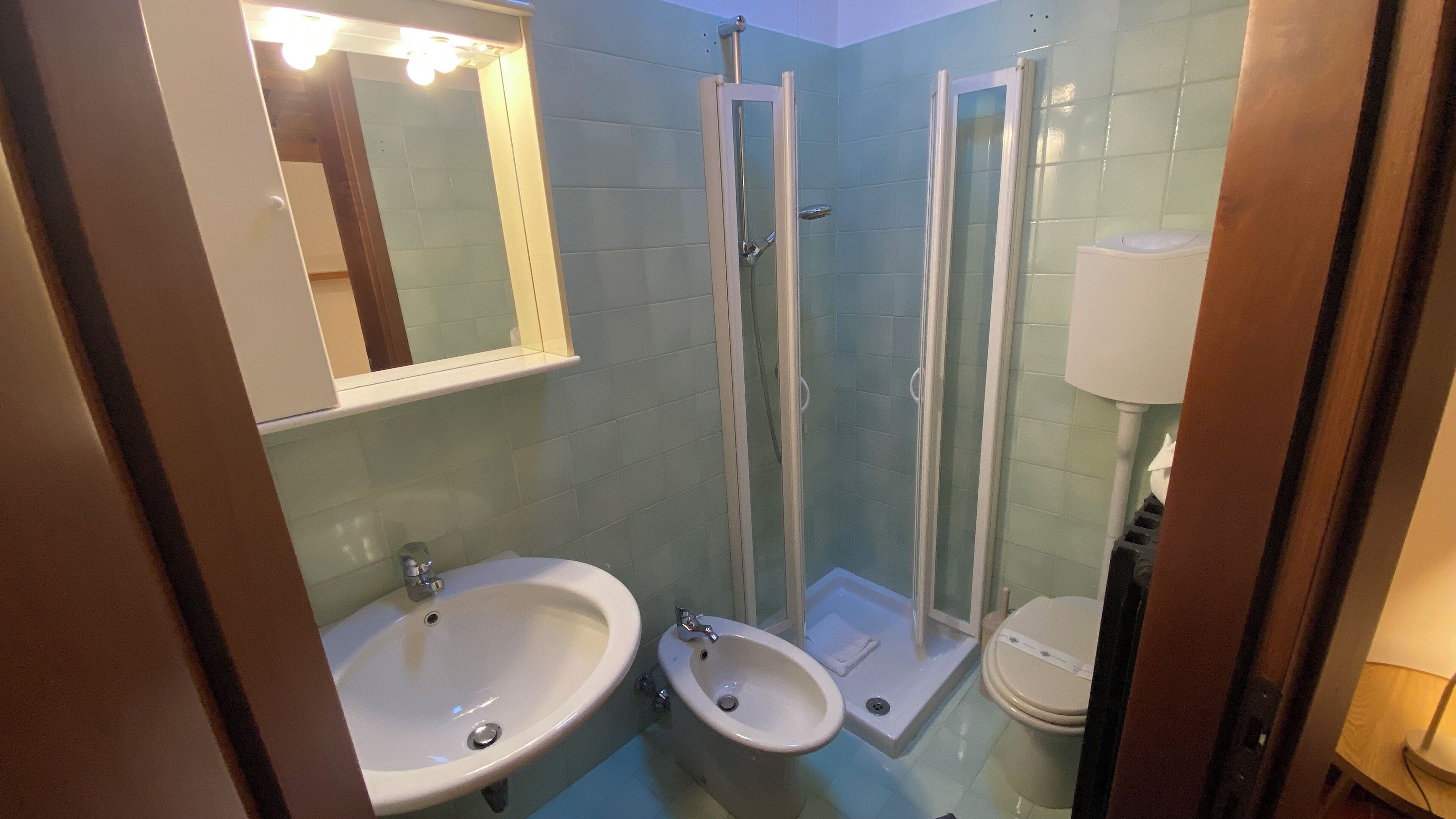 Un baño con lavamanos, bidé y ducha con mampara de vidrio.