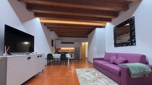 Um apartamento moderno com área de jantar, sala de estar com sofá roxo e cozinha ao fundo.