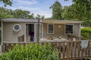 A mobile home with a deck, a small porch, and a window.