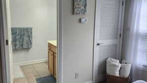 A bathroom with a towel rack, a decorative sign, a thermostat, and a basket with towels.
