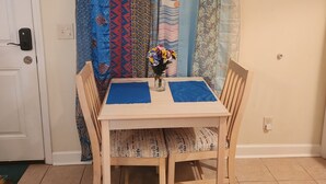 A dining table with two chairs, a vase with flowers, and a curtain with various patterns.