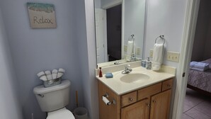 A bathroom with a toilet, sink, and mirror.