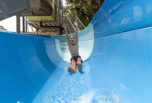 Eine Person saust eine blaue Wasserrutsche hinunter.