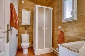 Bathroom features a white toilet, shower enclosure, and bathtub with shower head.