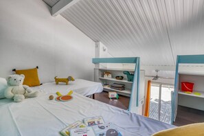 Une chambre d’enfant avec des lits superposés, une bibliothèque et des jouets.