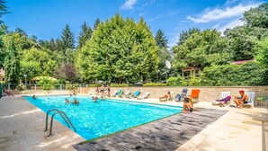 Una piscina con cubierta de madera, rodeada de exuberante vegetación y árboles.