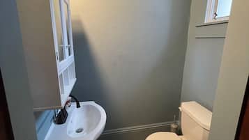 Une petite salle de bain compacte, avec un lavabo blanc, des toilettes et un meuble avec un miroir.