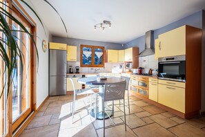 Een moderne keuken met een eethoek, grote ramen en uitzicht op bergen.