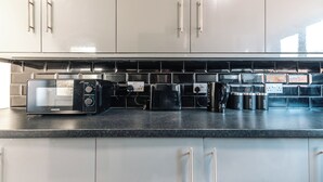 A kitchen with a black countertop, a microwave, a coffee maker, and a kettle.