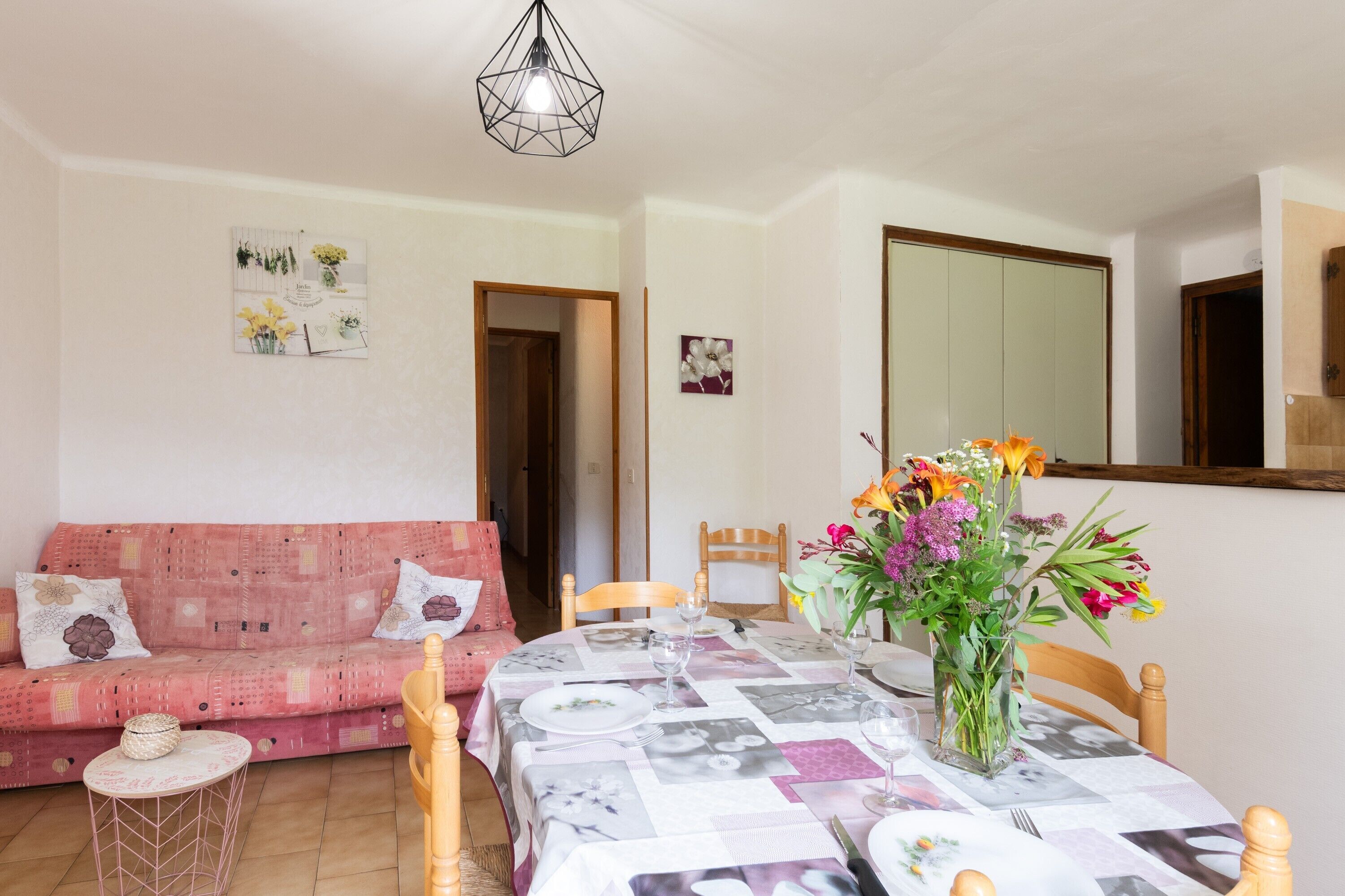 Ein Essbereich mit Tisch für zwei Personen, einem rosa Sofa und einem Spiegel an der Wand.